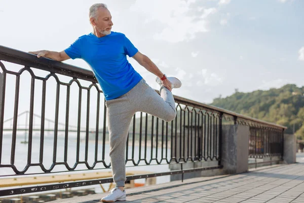 Hombre mayor estirando los músculos de las piernas antes de correr por la mañana — Foto de Stock