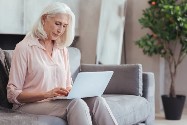 Nette alte Frau mit ihrem Laptop zu Hause — Stockfoto