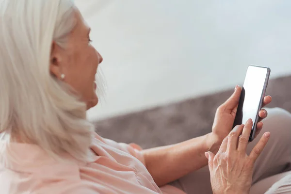 Весела старша жінка використовує свій смартфон вдома — стокове фото