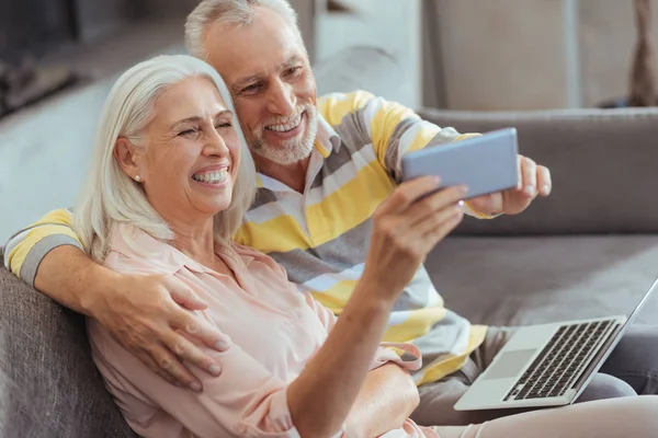 Örömmel mosolyogva idősebb pár-így selfies otthon — Stock Fotó