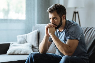 Mutsuz sakallı adam kanepede oturan