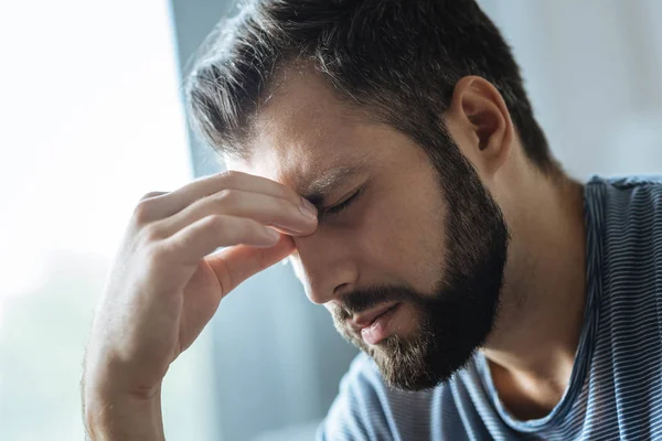 喜怒无常的年轻男子，拿着他的鼻子的桥梁 — 图库照片