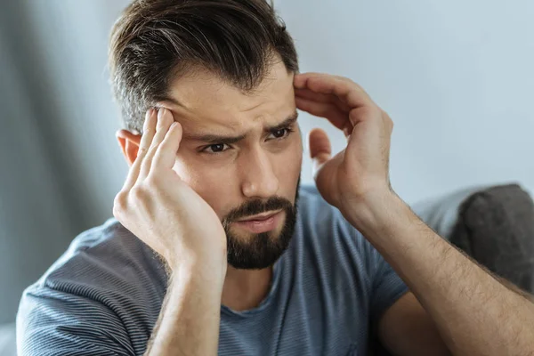 Cheerless unhappy man massaging his temples — Stock Photo, Image