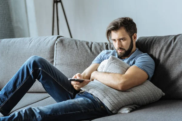 Sad lonely man holding a remote control — Stock Photo, Image