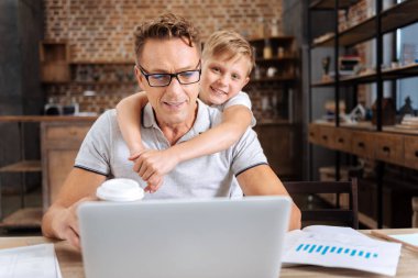 Mutlu çocuk babası o üstünde laptop çalışma sırasında sarılma