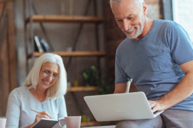 Onun laptop kullanan neşeli yaşlı adam