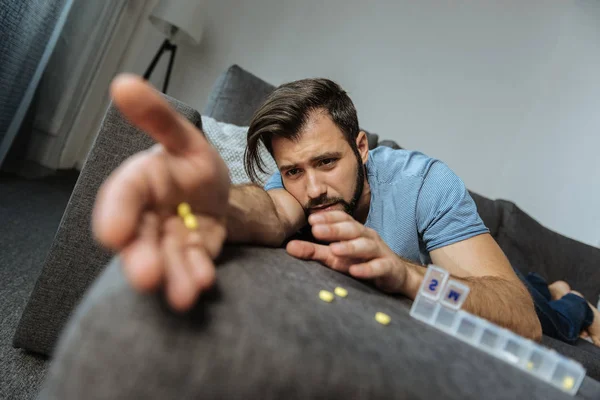 Нещасний примхливий чоловік намагається дістатися до своїх ліків — стокове фото