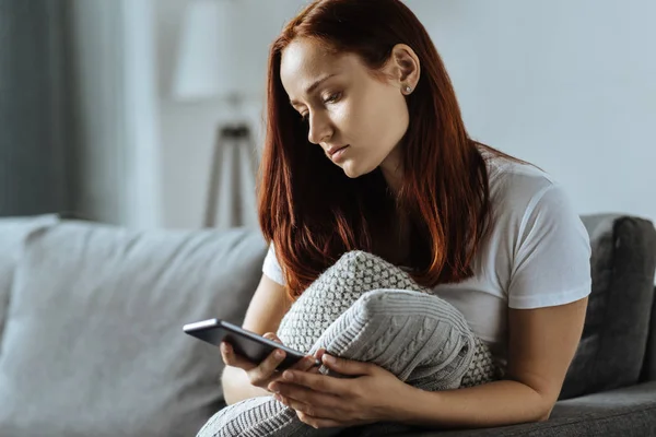 Mujer joven triste sosteniendo su teléfono inteligente — Foto de Stock