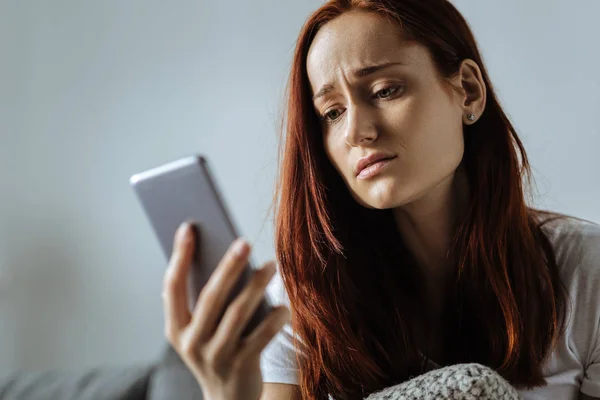 Cheerless giovane donna guardando il suo telefono — Foto Stock