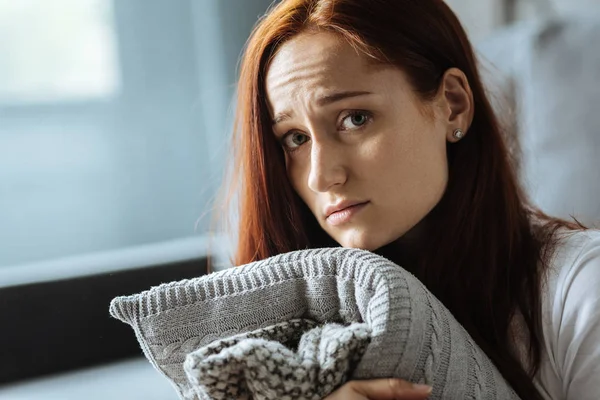 Triste mulher ruiva segurando uma almofada — Fotografia de Stock