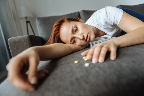 Hermosa mujer infeliz tratando de llegar a sus pastillas — Foto de Stock