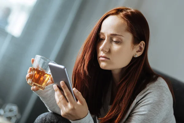 Trevliga sorglig kvinna som håller ett glas whisky — Stockfoto