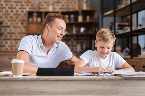 Omtänksam far övervaka hans son gör läxor — Stockfoto