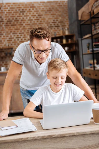 Genç baba oğlu iş üstünde laptop izlerken