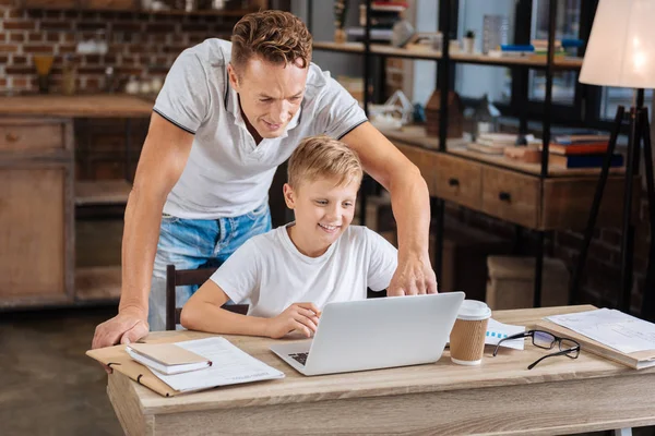 Заботливый отец помогает сыну с настройками ноутбука — стоковое фото