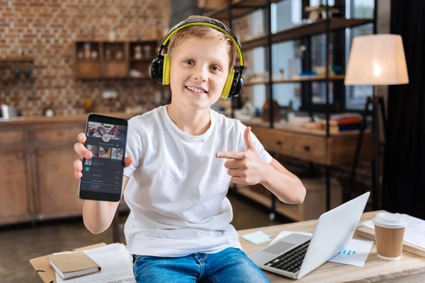 Sonriente chico mostrando su música favorita aplicación de streaming —  Fotos de Stock
