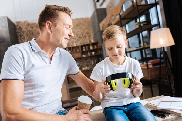 Liten pojke sitter nära far och tittar på hörlurar — Stockfoto