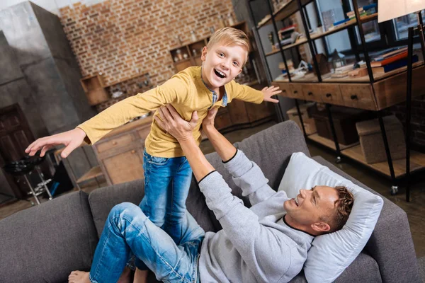 Fröhlicher Junge spielt mit seinem Vater auf dem Sofa — Stockfoto