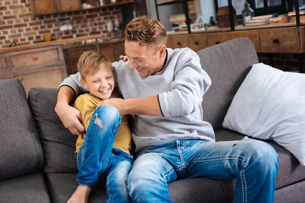 愛情のある父のソファの上に彼の幼い息子をくすぐり — ストック写真