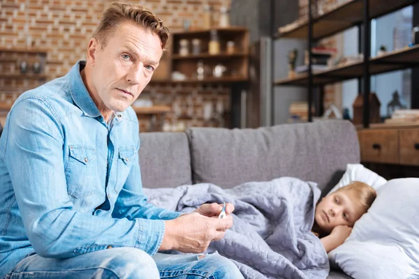 Ernstige vader controle van temperatuur van zijn zieke zoon — Stockfoto