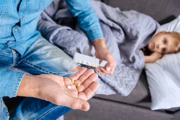 Cuidar padre sosteniendo pastillas para su hijo enfermo —  Fotos de Stock