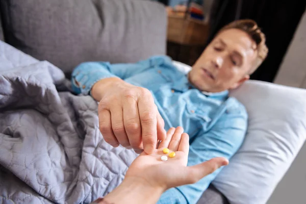 Hombre enfermo tomando pastillas de la mano de un niño — Foto de Stock