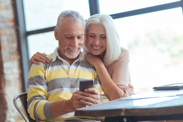 Casal de idosos positivos usando seu telefone inteligente — Fotografia de Stock