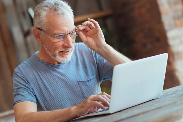 Hombre anciano concentrado usando el ordenador portátil en casa — Foto de Stock