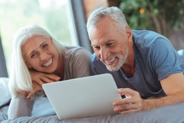 Fröhlicher alter Mann, der mit seiner Frau im Bett liegt — Stockfoto