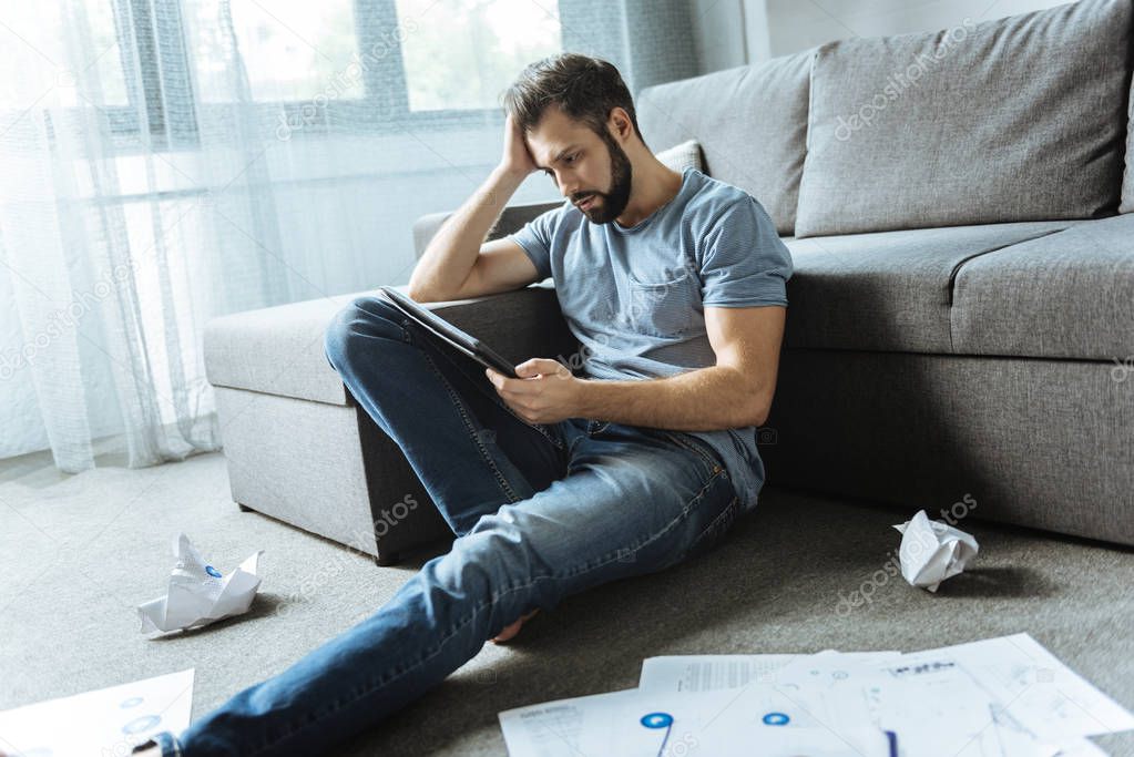 Sad cheerless man using a tablet