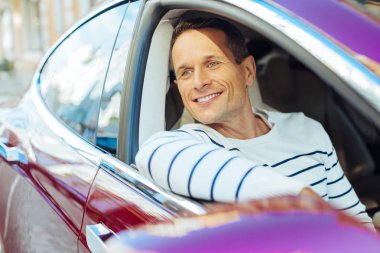 Mutlu mutlu adam arabasında oturuyor