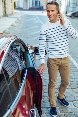 Arabanın kapısını tutarak olumlu iyi görünümlü bir adam