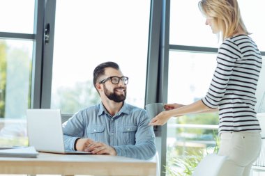 Onun meslektaşım için bir fincan kahve sunan bakım kadın