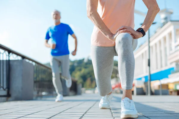 Close up of senior woman doing lunges in the street — Stock Photo, Image