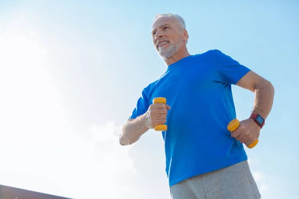 Piacevole uomo anziano in possesso di manubri e jogging — Foto Stock