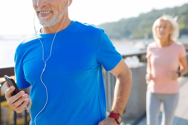 Primer plano del hombre mayor escuchando música mientras corre — Foto de Stock