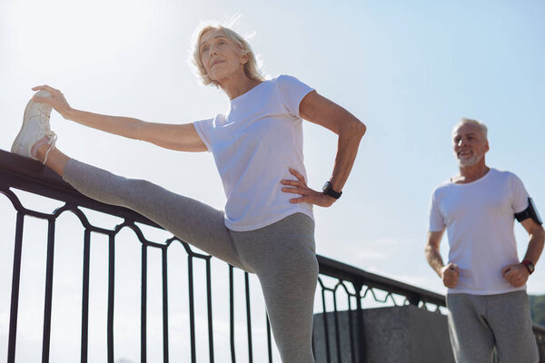 Athletic woman stretching while her husband running