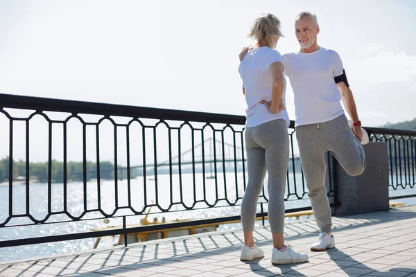 Fit man stretching with the help of his wife — Stock Photo, Image