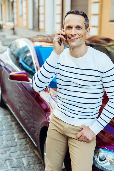 Positivo hombre encantado poniendo un teléfono celular a su oído — Foto de Stock