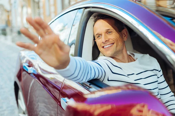 Örömteli, szép ember a kocsi ablakából integet — Stock Fotó