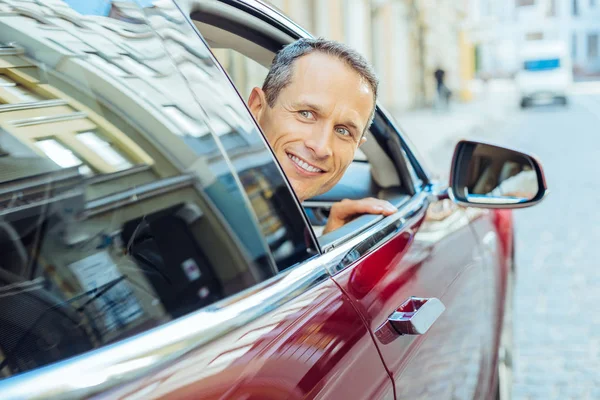 Encantado hombre alegre poniendo su cabeza de la ventana — Foto de Stock