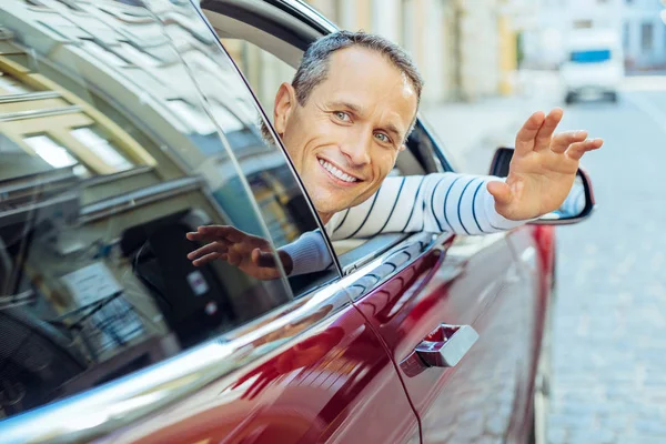 Alegre hombre positivo poniendo su mano de la ventana del coche — Foto de Stock