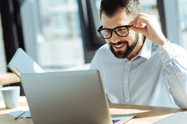 Uśmiechnięty mężczyzna patrząc na laptopa trzymając notebook — Zdjęcie stockowe