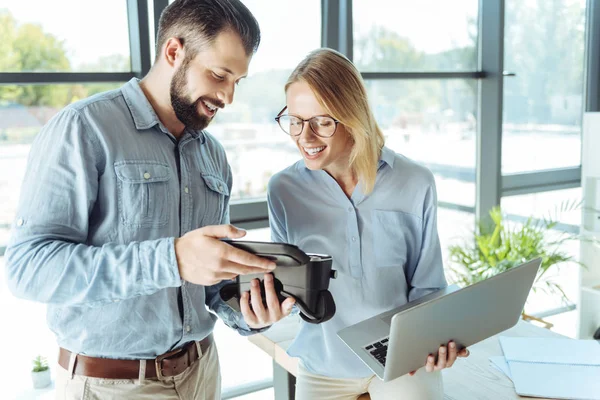 Dos colegas sonrientes mirando dentro de los auriculares VR — Foto de Stock