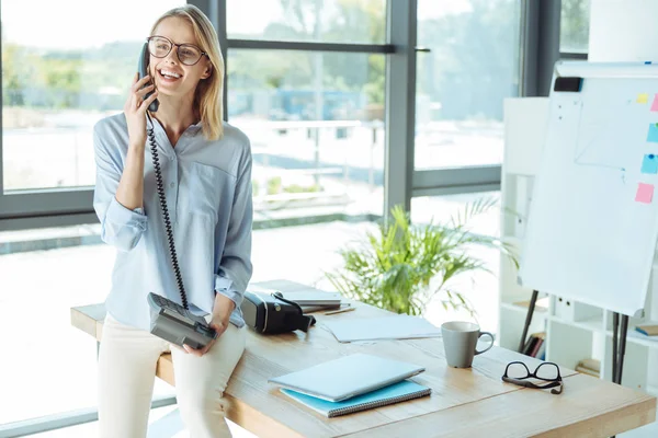 Joyful pretty woman talking on the landline phone in office — Stock Photo, Image