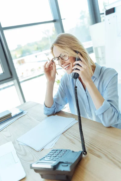 Young businesswoman adjusting spectacles while talking on phone — Stock Photo, Image