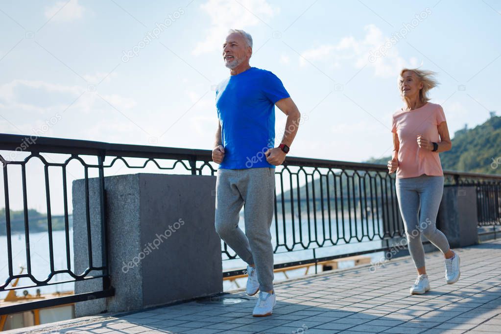 Senior woman following her upbeat husband during morning run