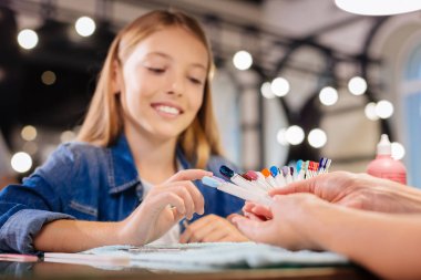 Gülümseyen kız onun gelecekteki manikür için bir çivi tasarım toplama
