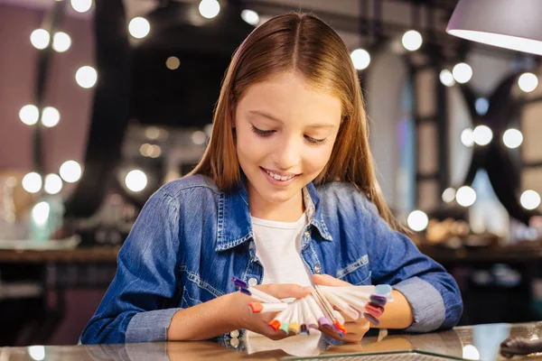 Chica adolescente mirando a través de una paleta de exhibición de diseño de uñas — Foto de Stock