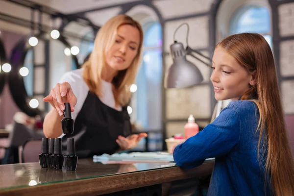 Charming manicurist suggesting nail polish color to her client — Stock Photo, Image